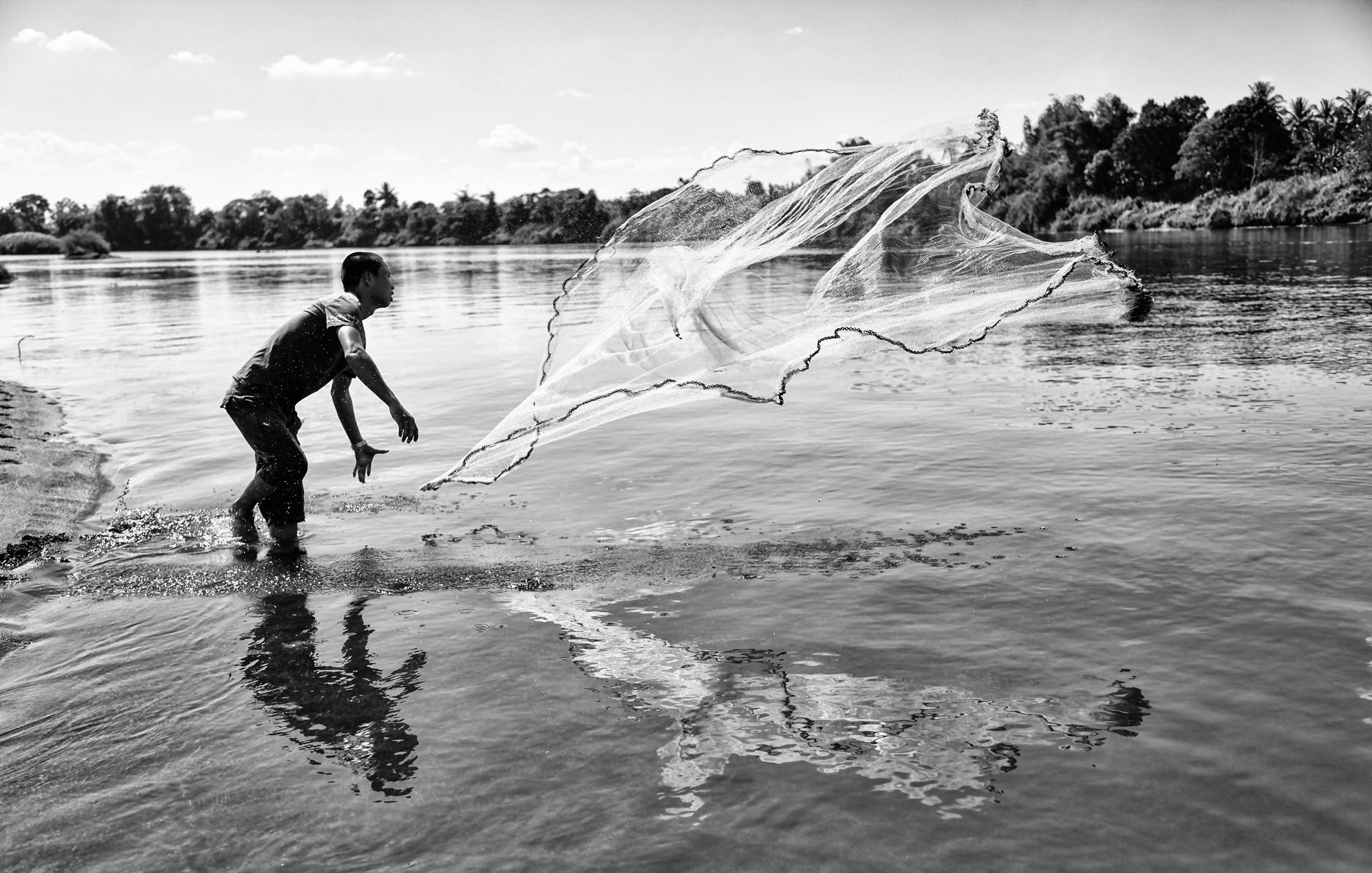 grayscale photo of man throwing a fishing net